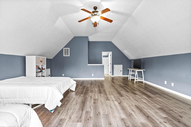 unfurnished bedroom featuring vaulted ceiling, wood finished floors, visible vents, and baseboards