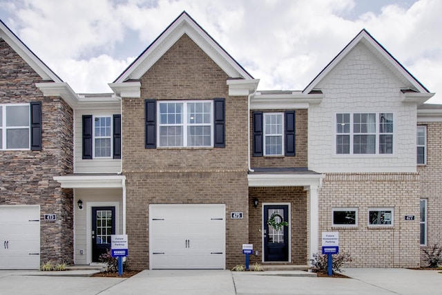 multi unit property with a garage, concrete driveway, and brick siding