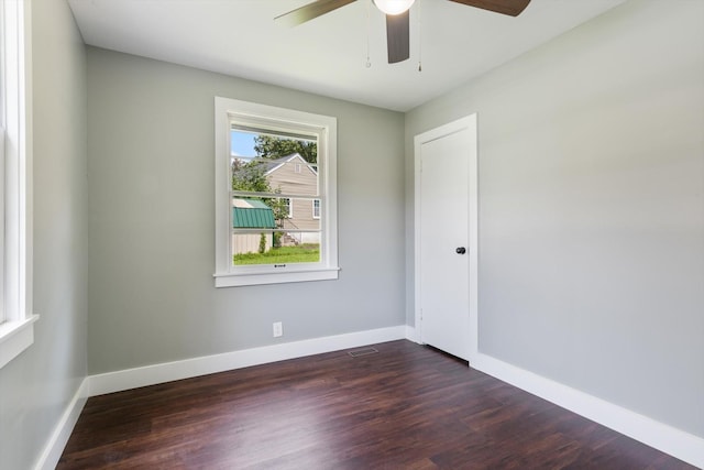 spare room featuring dark wood-style flooring, visible vents, and baseboards