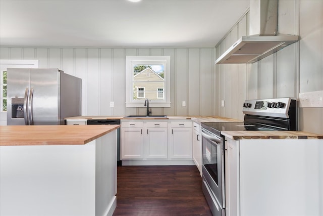 kitchen with butcher block counters, white cabinetry, stainless steel appliances, and a sink