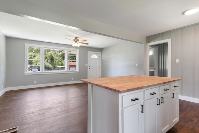 kitchen with a center island, dark wood finished floors, wooden counters, open floor plan, and white cabinets