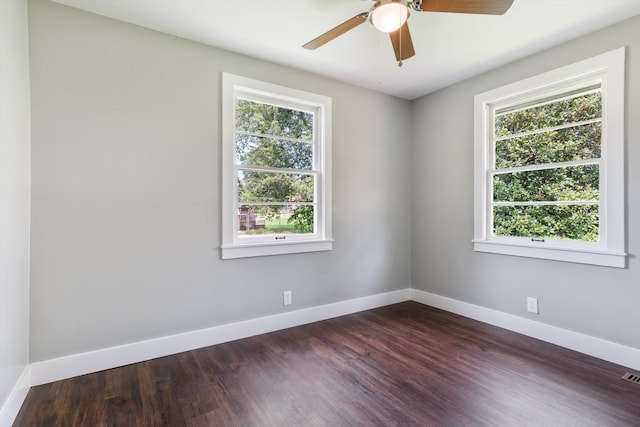 empty room featuring a wealth of natural light, dark wood finished floors, and baseboards