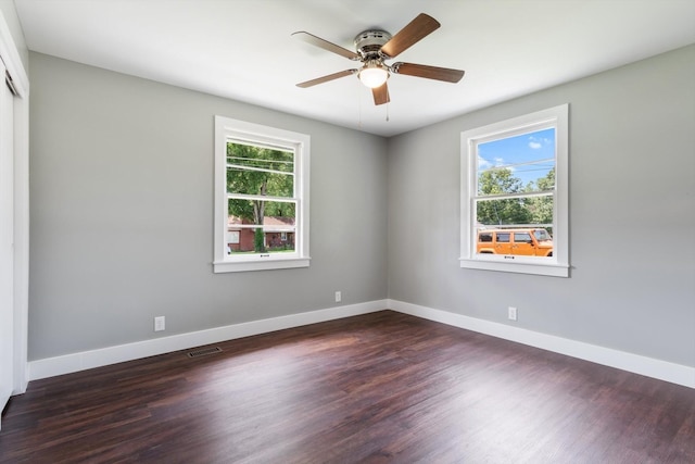 unfurnished room with baseboards, visible vents, ceiling fan, and dark wood-style flooring