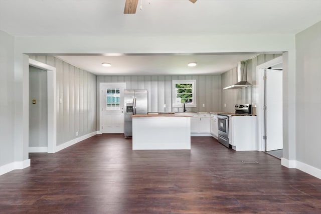 kitchen featuring a kitchen island, white cabinetry, light countertops, appliances with stainless steel finishes, and wall chimney range hood