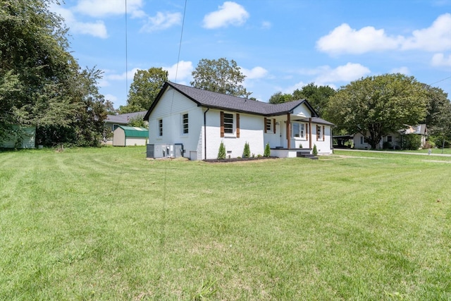 view of front of house with a storage shed, brick siding, a porch, and a front yard