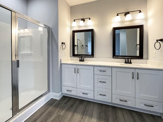 full bath featuring double vanity, wood finished floors, a sink, and a shower stall