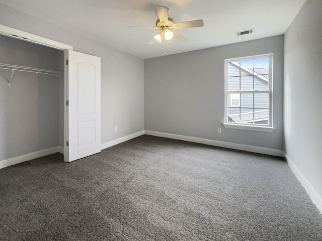 unfurnished bedroom with dark colored carpet, a closet, visible vents, and baseboards