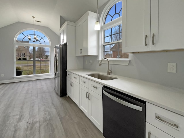 kitchen with pendant lighting, light countertops, a sink, and dishwashing machine