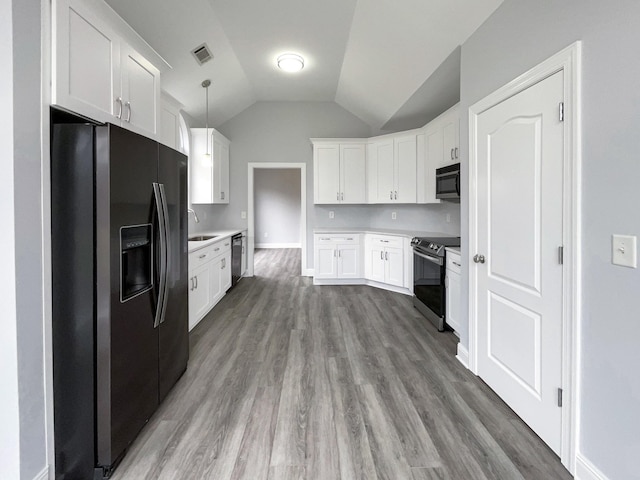 kitchen featuring wood finished floors, hanging light fixtures, stainless steel appliances, light countertops, and white cabinetry