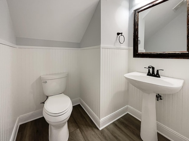 bathroom featuring lofted ceiling, a sink, wood finished floors, and toilet