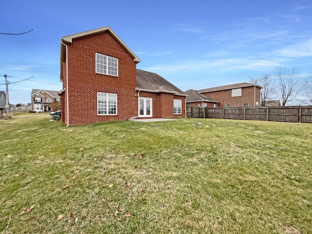 rear view of property with brick siding, a yard, and fence