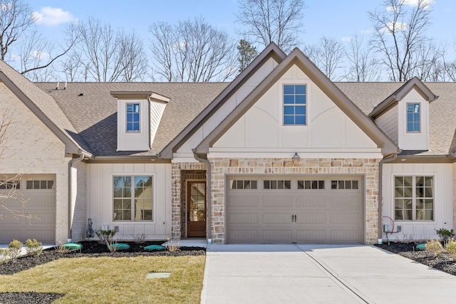 view of front of property featuring a garage, stone siding, board and batten siding, and roof with shingles