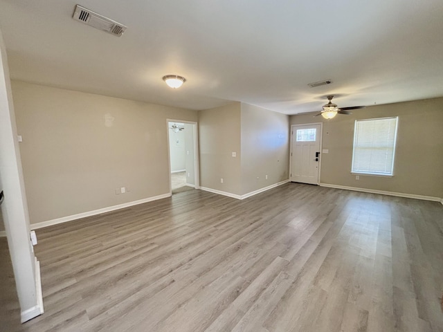 unfurnished living room with baseboards, visible vents, ceiling fan, and wood finished floors