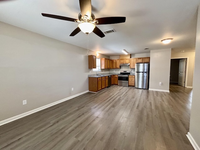 kitchen featuring under cabinet range hood, a sink, visible vents, baseboards, and appliances with stainless steel finishes