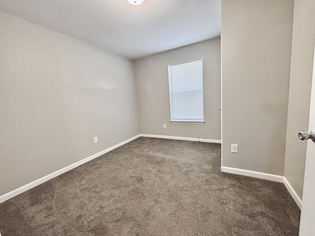 empty room with baseboards and dark carpet