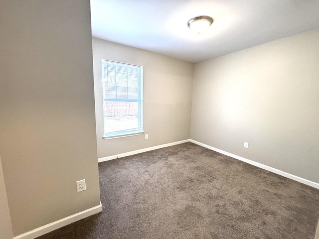 spare room featuring baseboards and dark colored carpet