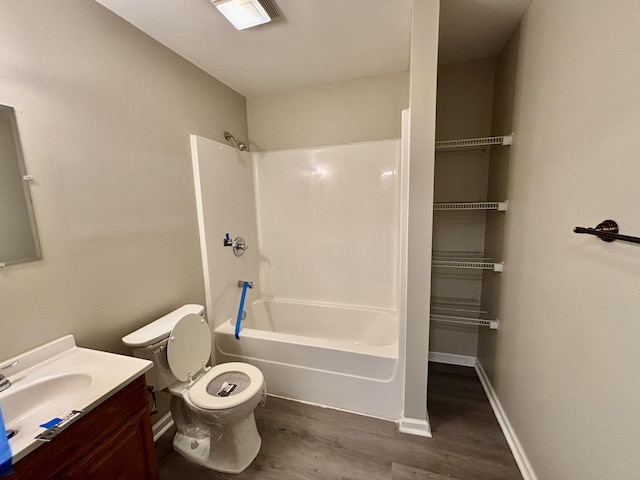 bathroom with shower / tub combination, toilet, wood finished floors, vanity, and baseboards