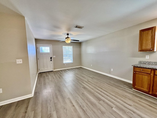 interior space with a ceiling fan, visible vents, baseboards, and wood finished floors