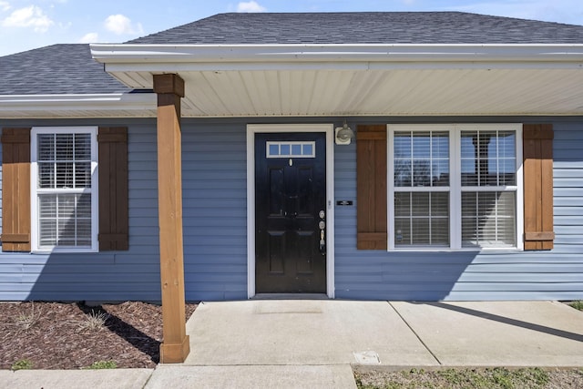 entrance to property with a shingled roof and covered porch