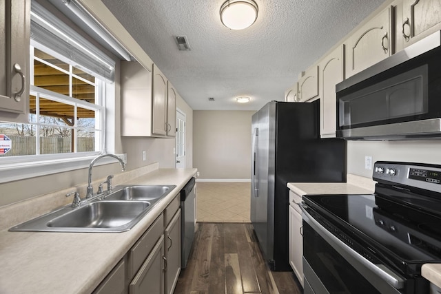 kitchen with stainless steel appliances, light countertops, visible vents, a sink, and a textured ceiling