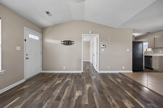 entrance foyer with dark wood-style floors, lofted ceiling, visible vents, and baseboards