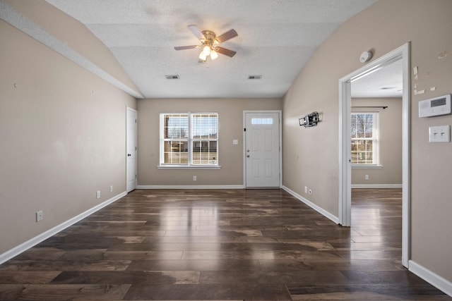 foyer entrance with lofted ceiling, a textured ceiling, dark wood finished floors, and visible vents