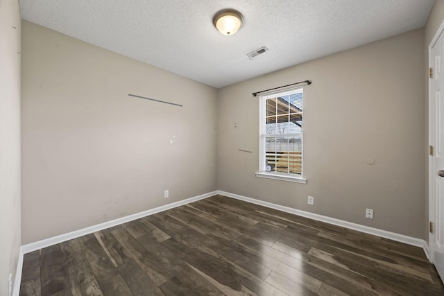 unfurnished room featuring baseboards, visible vents, and dark wood-type flooring