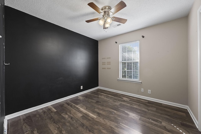 unfurnished room featuring a textured ceiling, a ceiling fan, visible vents, baseboards, and dark wood-style floors