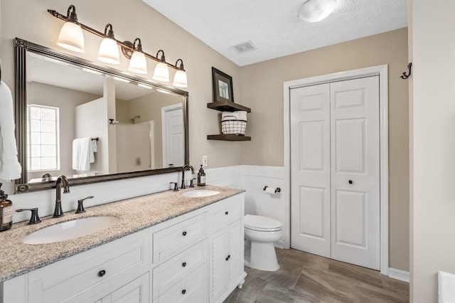 full bathroom with double vanity, visible vents, a sink, and walk in shower