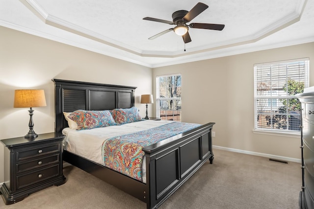 bedroom featuring light carpet, visible vents, baseboards, ornamental molding, and a tray ceiling