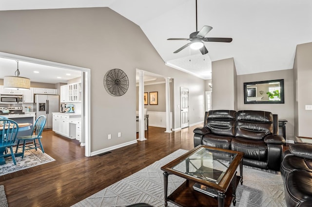 living room featuring ceiling fan, high vaulted ceiling, baseboards, dark wood finished floors, and ornate columns