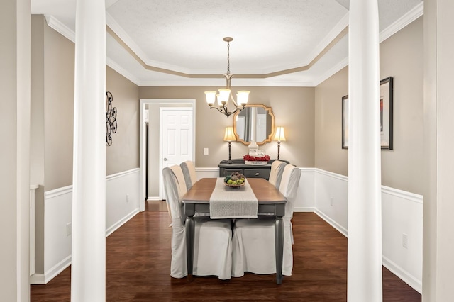 dining room with dark wood-style floors, a tray ceiling, crown molding, and a notable chandelier