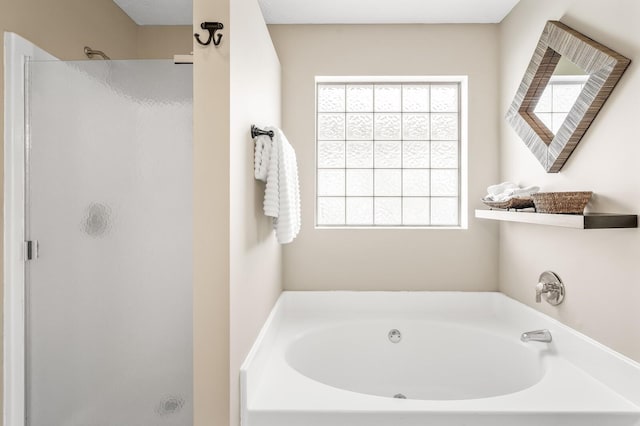 bathroom featuring a shower stall and a bath