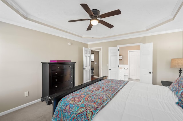 carpeted bedroom with ensuite bath, baseboards, a raised ceiling, and crown molding