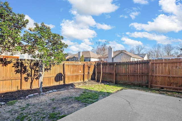 view of yard featuring a patio area, a fenced backyard, and a residential view