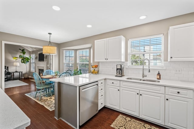 kitchen featuring a sink, dark wood finished floors, dishwasher, and a glass covered fireplace