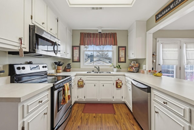 kitchen featuring stainless steel appliances, light countertops, a sink, and white cabinetry