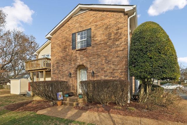 view of home's exterior with an outbuilding, a balcony, central air condition unit, a storage shed, and brick siding