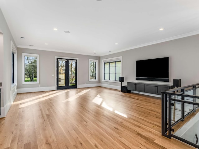 living room with light wood-style floors, baseboards, crown molding, and french doors