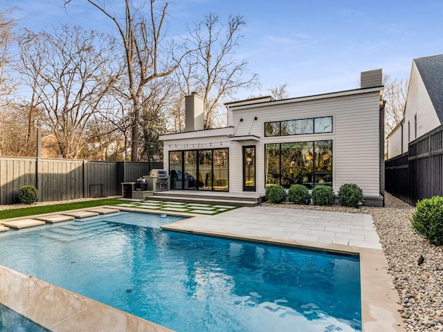 rear view of house with a fenced in pool, a fenced backyard, a patio, and a chimney