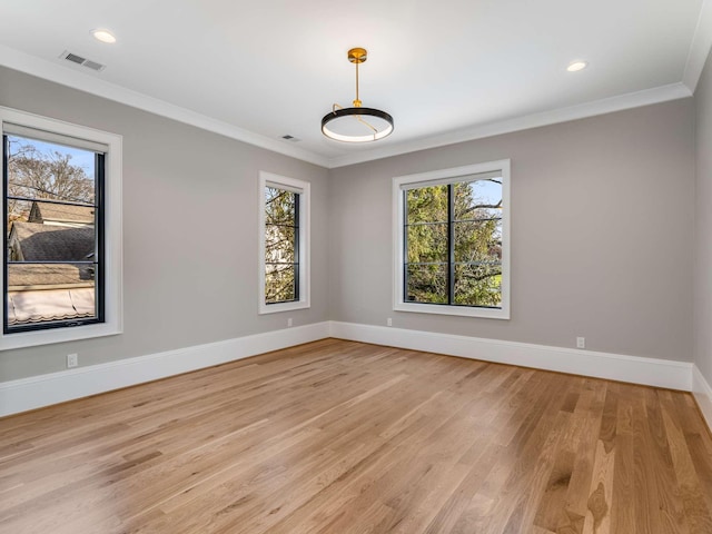 empty room with crown molding, plenty of natural light, visible vents, and baseboards