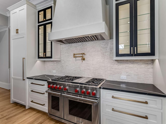 kitchen with dark countertops, double oven range, custom exhaust hood, and white cabinets