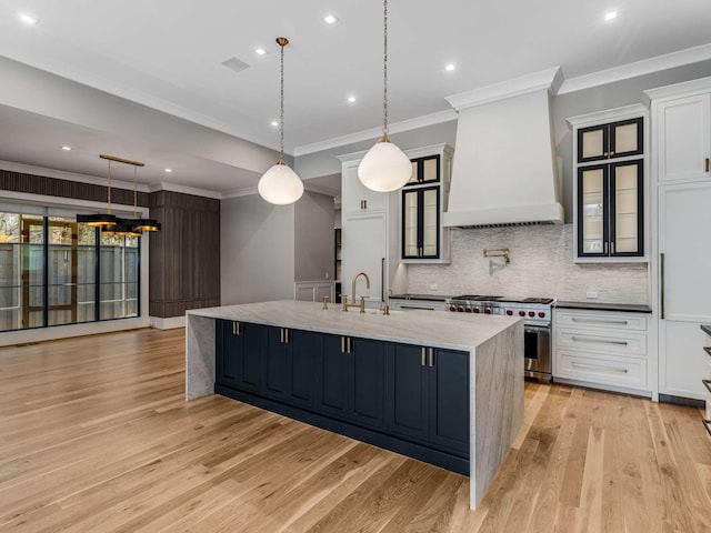 kitchen with glass insert cabinets, custom exhaust hood, decorative light fixtures, and high end stainless steel range