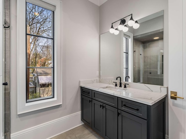 bathroom featuring tile patterned floors, a tile shower, vanity, and baseboards