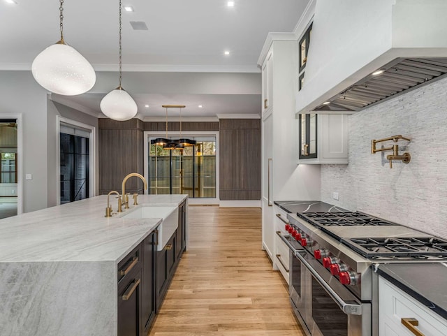 kitchen featuring decorative light fixtures, custom exhaust hood, white cabinetry, and double oven range