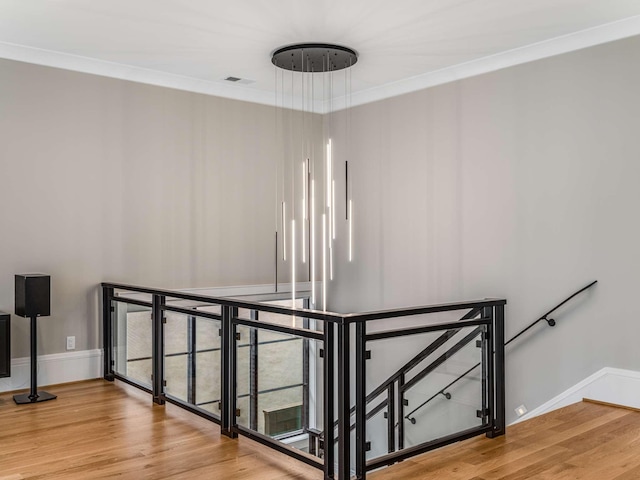 stairs featuring baseboards, wood finished floors, visible vents, and crown molding