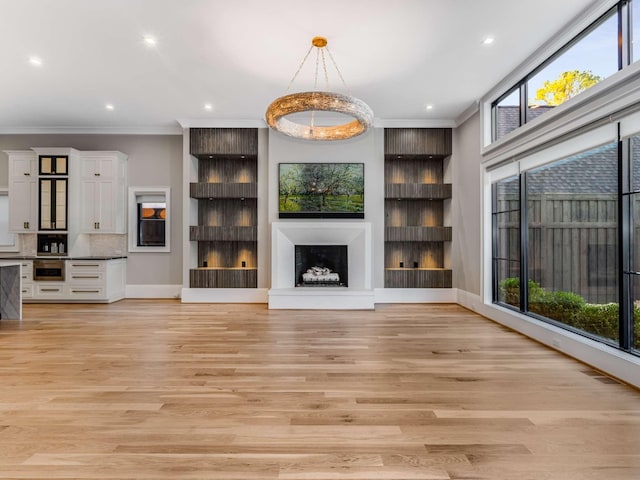 unfurnished living room featuring a fireplace with raised hearth, recessed lighting, light wood-style flooring, and crown molding