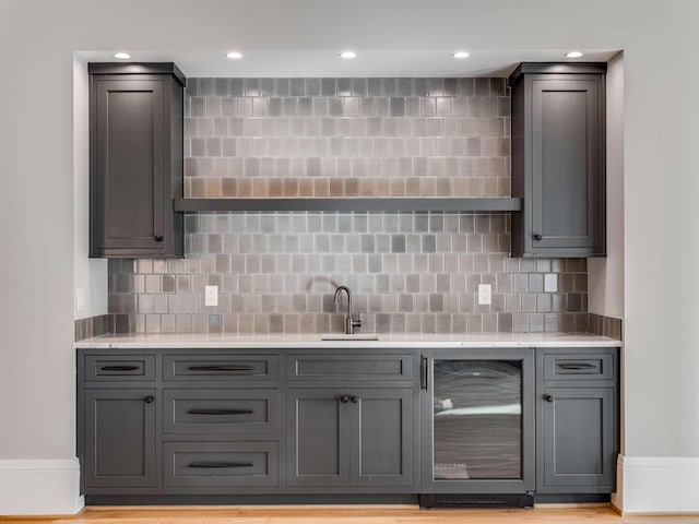 bar featuring wine cooler, recessed lighting, decorative backsplash, a sink, and wet bar