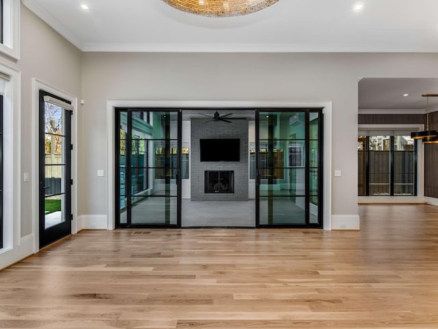 foyer entrance with baseboards, light wood-type flooring, a fireplace, and a healthy amount of sunlight