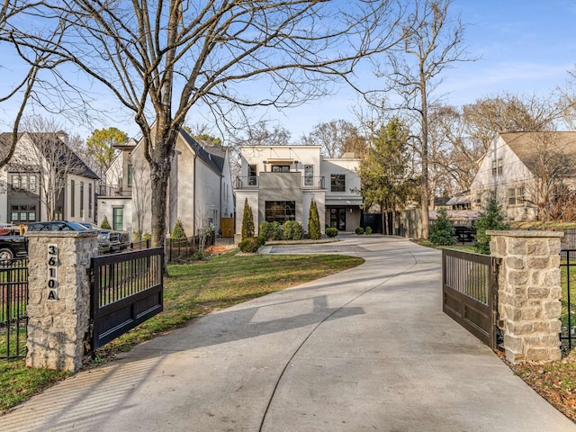 view of front of home with a fenced front yard, a balcony, a gate, a residential view, and a front lawn